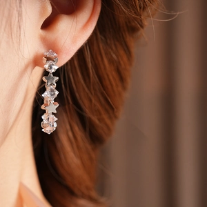 Detail shot of elegant silver star-shaped drop earrings with sparkling zircon on a model