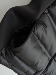 Close-up of black puffer vest featuring waterproof zipper and horizontal quilting details