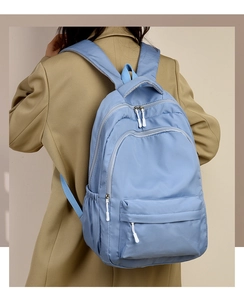 Detail view of smooth metal zippers and side pockets on a light blue nylon backpack