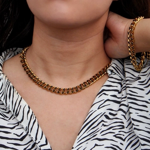 Detail of gold Cuban link chain necklace and bracelet set with black enamel accents on model