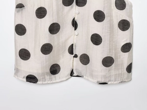 Detail of white polka dot top showing round buttons and lightweight fabric texture