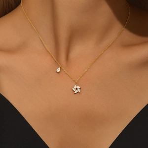 Detail of gold necklace featuring star and water drop zircon pendants on a model's neck