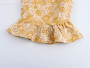 Detail der floralen Jacquard-Textur und des eleganten Volants am Saum eines ärmellosen Tops