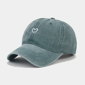 Close-up of heart embroidery on washed dark green cotton baseball cap fabric texture