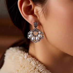Close-up of vintage-style pearl drop earring with rhinestones on a female model
