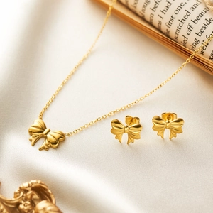 Detail shot of golden ribbon bow jewelry set with necklace and earrings on white silk