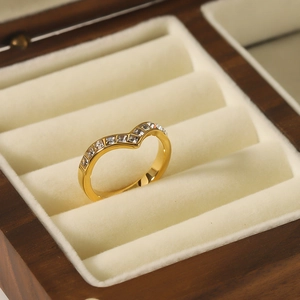 Polished gold V-shaped ring with pavé zircons displayed on a wooden jewelry box