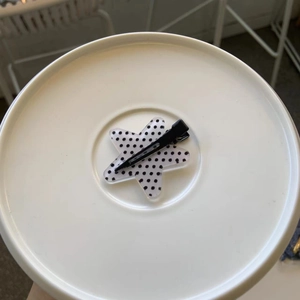 Detail of star-shaped duckbill hair clip with black and white polka dot pattern design