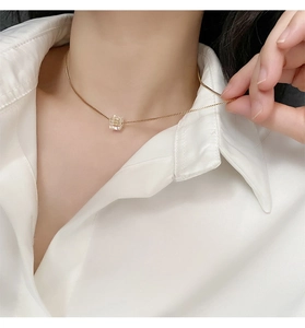Dettaglio della collana in titanio dorato con ciondolo a cubo di cristallo geometrico