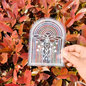Close-up of rainbow prism suncatcher sticker with butterfly and mushroom patterns