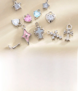 Macro view of silver cross and heart charms with enamel and cubic zirconia details