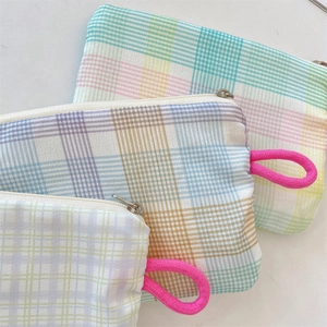 Detailed macro view of three plaid canvas pouches with zippers and pink rope handles