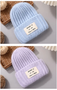 Detail of sky blue and lilac rabbit hair knit beanies with textured fabric patches