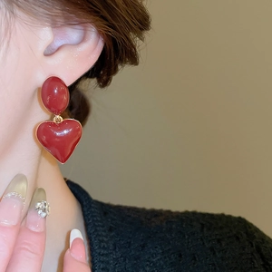 Close-up of elegant red oval heart earrings with gold trim worn by a model