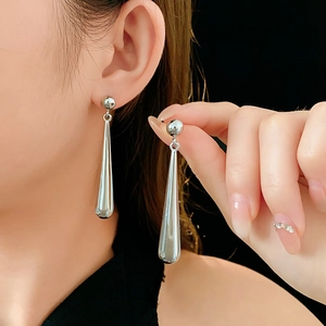 Macro shot of silver teardrop earrings showing high-shine mirror finish on model