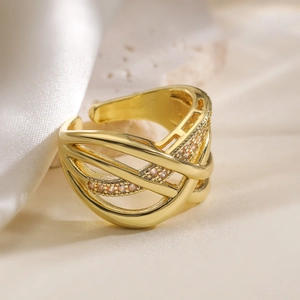 Intertwined geometric gold ring with pave crystals on soft silk background