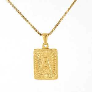 Macro shot of gold rectangular pendant with letter A and sunburst texture on box chain