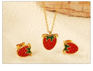 Detailed view of red strawberry pendant necklace and matching earrings set on beige background