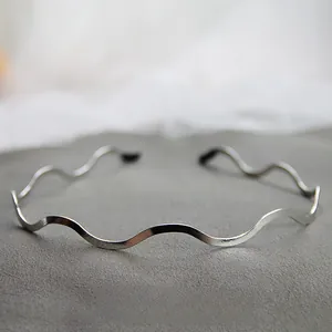 Dettaglio ravvicinato di un cerchietto ondulato in metallo lucido color argento