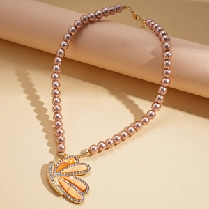 Détail du collier de perles roses avec pendentif aile de papillon serti de strass