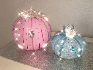Close-up of pink and blue decorative pumpkins with sparkling rhinestones and silver crowns