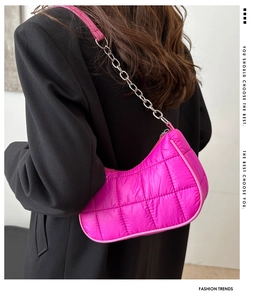 Detail of hot pink quilted nylon underarm bag with silver chain strap on black suit