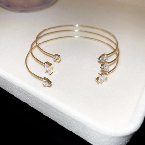 Detailed close-up of three gold-plated bangle bracelets featuring zircon star and heart shapes