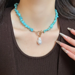 Close-up of bohemian turquoise beaded necklace with baroque pearl pendant and golden OT clasp