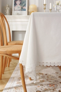 Detail of white cotton tablecloth featuring elegant lace edges in a French vintage setting