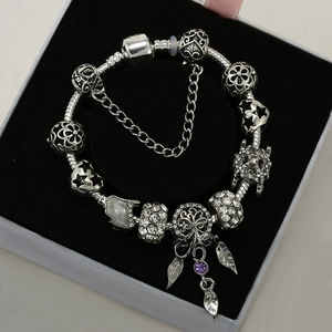 Close-up of DIY silver charm bracelet with Tree of Life pendant and purple zircon stones