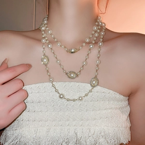 Detail of elegant multi-layered pearl necklace with crystal-embellished oval charms
