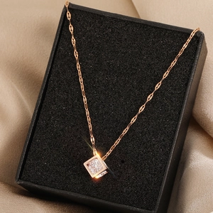 Rose gold necklace with square zircon pendant in a black gift box on beige silk