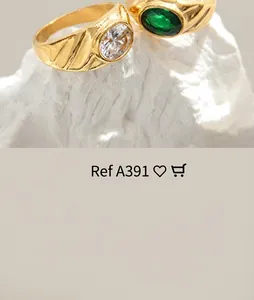 Detailed shot of gold-plated wide rings featuring green and white gems on a white stone