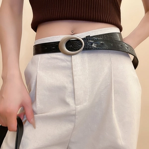 Close-up of black crocodile pattern leather belt with vintage round silver metal buckle