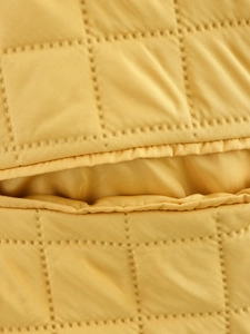 Macro view of bright yellow quilted fabric with detailed grid patterns and tight stitching