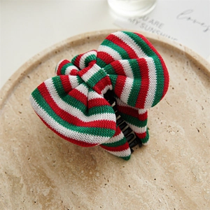 Detailed view of large knitted bow hair clip in festive red, green and white Christmas stripes