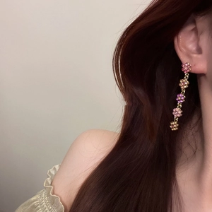 Détail de boucles d'oreilles florales avec cristaux roses et finition dorée