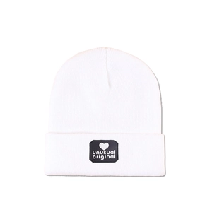 Detail of white knit beanie with black heart shield patch and unusual original text