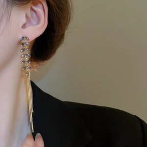 Close-up of elegant long tassel earrings with blue crystals and gold leaf design