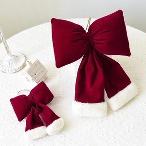 Large and small red velvet Christmas tree bows with white faux fur trim on white tablecloth