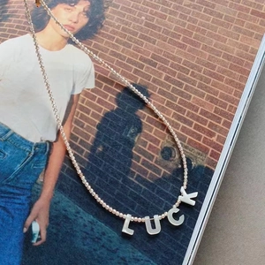 Detail of beaded necklace with LUCK letter charms on a fashion magazine backdrop