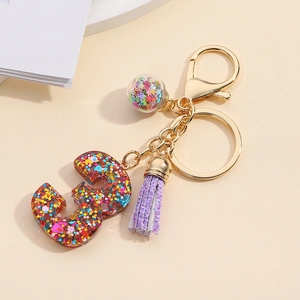Detail of glitter resin number 3 keychain with purple tassel and star glass ball charm