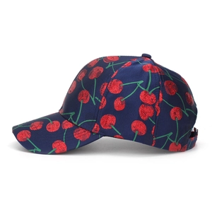 Close-up of sparkling sequined red cherry embroidery on a navy blue baseball cap fabric