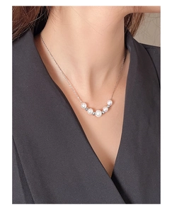 Macro view of dainty S925 silver necklace with baroque freshwater pearls on a model