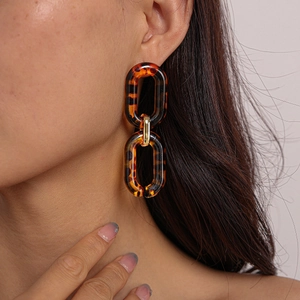 Close-up of leopard print acrylic chain earrings with golden metal connectors on a model