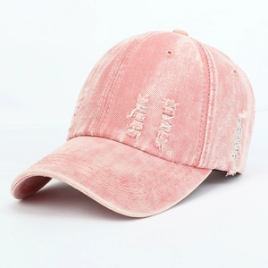 Close-up view of a pink washed denim baseball cap featuring stylish distressed ripped details