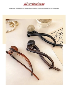 Detailed view of three resin banana clips in black, brown, and amber on a decorative desk