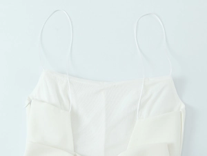 Close-up of white mini dress fabric showing thin shoulder straps and invisible side zipper