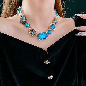 Close-up of vintage necklace featuring blue gemstones and white pearls on black velvet