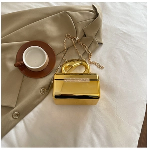 Close-up of golden mirror finish acrylic evening bag with metal handle and chain